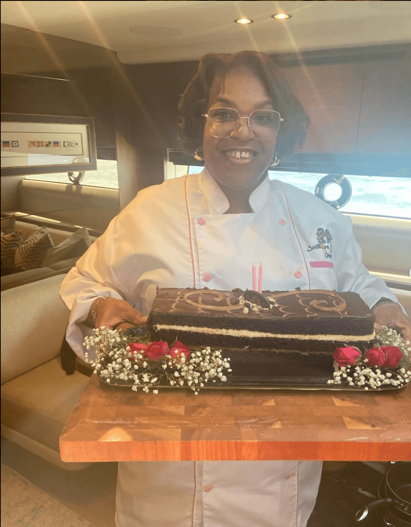 Chef portrait - Professional chef in white coat with pink trim, holding a chocolate cake